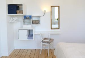 a white bedroom with a chair and a mirror at Die schöne Auguste in Oldenburg