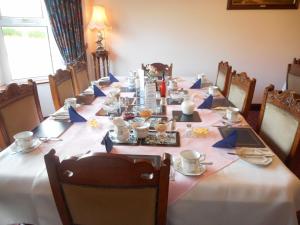 a long table with chairs and a long table with dishes at Springfield House B&B in Clonakilty