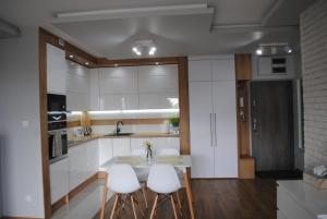 a kitchen with white cabinets and a table with stools at Apartament Żeglarski Wilkasy in Wilkasy