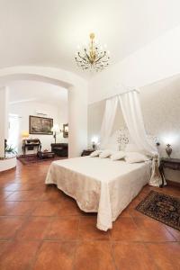 a bedroom with a white bed with a chandelier at Palazzo Castelleschi in Tarquinia