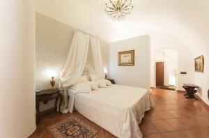 a bedroom with a white bed and a chandelier at Palazzo Castelleschi in Tarquinia