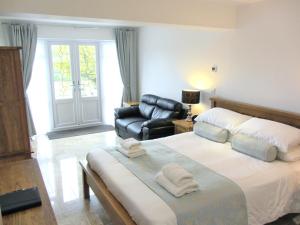 1 dormitorio con 1 cama grande y silla de cuero en Horsemanstone, en Amroth