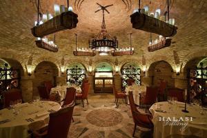 a restaurant with white tables and chairs and a chandelier at Halasi Pince Panzió in Villány