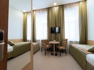 a hotel room with two beds and a table and a tv at Center Hotel in Saint Petersburg