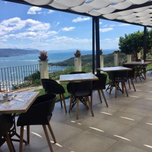 un patio con tavoli, sedie e vista sull'oceano di Le Ville Relais a La Spezia