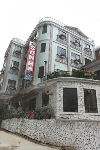 a tall white building with a stone wall at Son Ha Hotel SAPA in Sapa