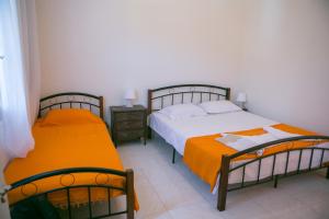 a bedroom with two beds with orange sheets at Theodora in Panormos