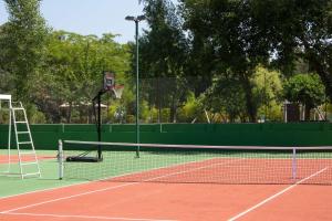 una pista de tenis con una red y un aro de baloncesto en La Villa Vicha, The Originals Relais, en Aubais