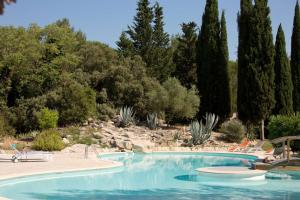 - une piscine dans un complexe avec des chaises et des arbres dans l'établissement La Villa Vicha, The Originals Relais, à Aubais