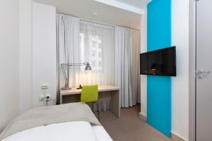 1 dormitorio con 1 cama, escritorio y TV en MediInn Hotel Oslo en Oslo