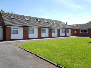 a row of white garage doors on a brick building at Chelford Guesthouse in Marthall