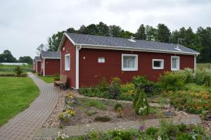 a red house with a garden in front of it at Guest House Kalnu pūpoli in Šengeida