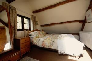 a bedroom with a bed and a dresser and window at Barn Cottage in Brecon