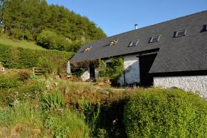eine Scheune mit schwarzem Dach und einigen Büschen in der Unterkunft Barn Cottage in Brecon