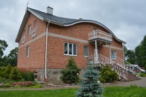 a large brick building with a porch and a balcony at Guest House Kalnu pūpoli in Šengeida