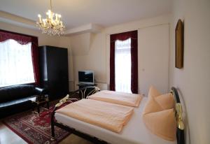 a bedroom with a bed and a couch and a chandelier at Hotel Zu den Linden in Dresden