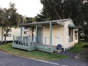a small house with a porch on the grass at Pinewood Caravan Park in Heywood
