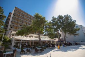 a patio with tables and chairs and a building at Hotel Dražica - Hotel Resort Dražica in Krk