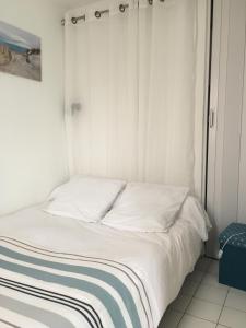 a bed with white sheets and a blue and white blanket at residence parc de pontaillac in Vaux-sur-Mer +7 photos