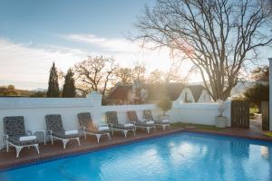 a swimming pool with lounge chairs and a fence at Laborie Jonkershuis in Paarl