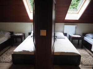 two beds in a small room with two windows at Willa Zacisze - Apartament dwupoziomowy in Kalwaria Zebrzydowska