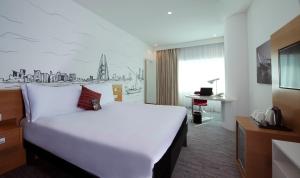 ibis Styles Manama Diplomatic Area في المنامة: غرفة في الفندق مع سرير أبيض كبير ومكتب