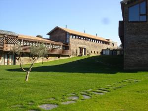 un bâtiment en briques avec un arbre dans l'herbe dans l'établissement Hospederia Parque de Monfragüe, à Torrejón el Rubio