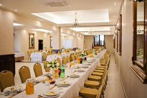 a long dining room with white tables and chairs at Hotel Victoria in Lubowo