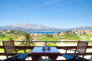 a table and chairs on a balcony with a view of the ocean at House Baglija in Lumbarda