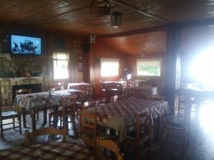 a dining room with tables and chairs and a tv at Livadaki Village in Megáli Kápsi