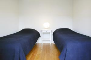two beds in a room with a night stand and a table at Boavista Apartment (Mercado da Ribeira) in Lisbon