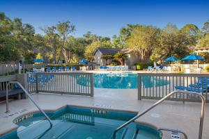 a swimming pool with chairs and umbrellas in a resort at Shipyard by Spinnaker Resorts in Hilton Head Island