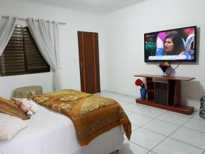 a bedroom with a bed and a flat screen tv at Pluma Hotel Cidade in Americana