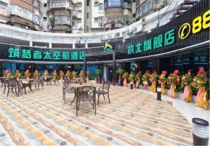 un groupe de personnes assises à des tables dans un bâtiment dans l'établissement Zhuhai Dreamers Capsule Hotel, à Zhuhai