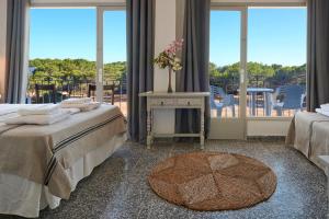 1 dormitorio con 2 camas, mesa y ventanas en Hotel Flamingo, en Es Canar