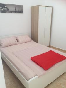 a white bed with a red blanket on it at Sisifou Apartment in Korinthos