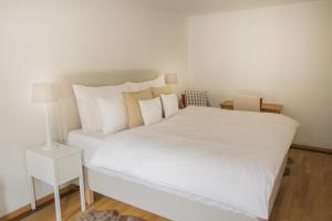 ein weißes Bett mit weißer Bettwäsche und Kissen in der Unterkunft Stylish Apartment in the Heart of Zug by Airhome in Zug