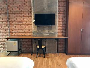 ein Zimmer mit einem Schreibtisch mit einem Fernseher an einer Ziegelwand in der Unterkunft De Nan Hotel in Nan + 7 Fotos