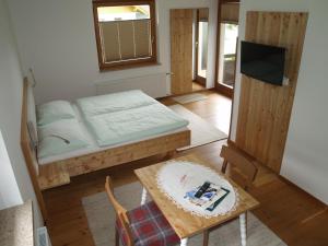 a small room with a bed and a table and a tv at Gästehaus Hubertus in Malta