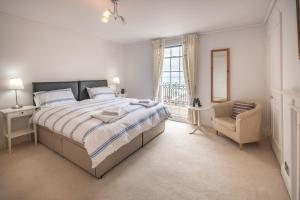 a bedroom with a bed and a chair and a window at Cliffhanger 18 Castle Road in Cowes