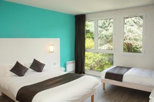1 dormitorio con 2 camas y ventana grande en Latitude Ouest Hotel Restaurant & Spa, en Locronan