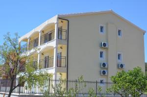 a white building with a fence in front of it at Apartments Neli in Vinišće