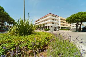 a building on a street with flowers in the foreground at Quadrangolo in Bibione