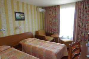 a hotel room with two beds and a table and a chair at Hotel Olymp in Sunny Beach