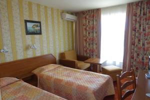Habitación de hotel con 2 camas, mesa y silla en Olymp Hotel en Sunny Beach