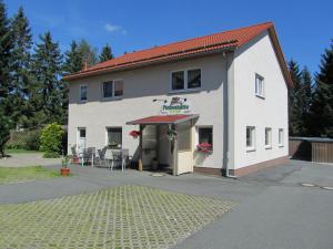 ein weißes Gebäude mit einem roten Dach und einer Terrasse in der Unterkunft Blechleppel - Die Pension im Harz in Benneckenstein