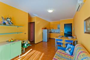 a living room with yellow walls and a kitchen at Quadrangolo in Bibione