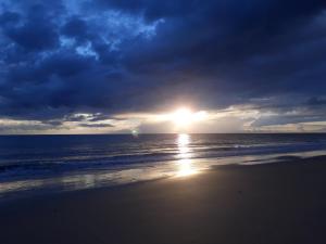 a sunset on a beach with the ocean and clouds at Pousada Pouso Da Praia in Cumbuco