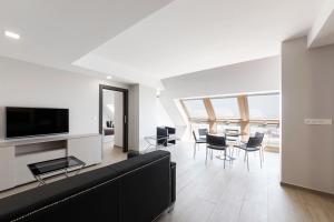 a living room with a black couch and chairs at Apartahotel A Cetárea in Burela de Cabo