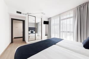 a bedroom with a large bed and a mirror at Apartahotel A Cetárea in Burela de Cabo